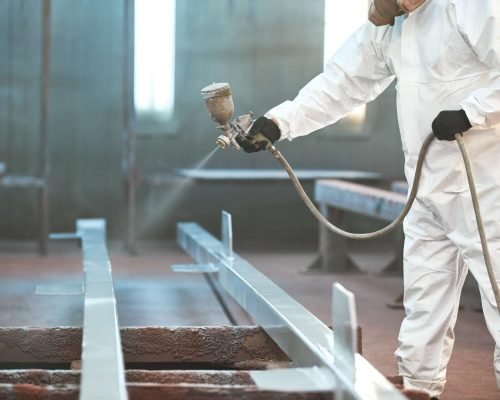 industrial painter in chamber painting metal detail for protection
